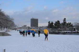 画像　雪景色の天王川公園で登校する児童