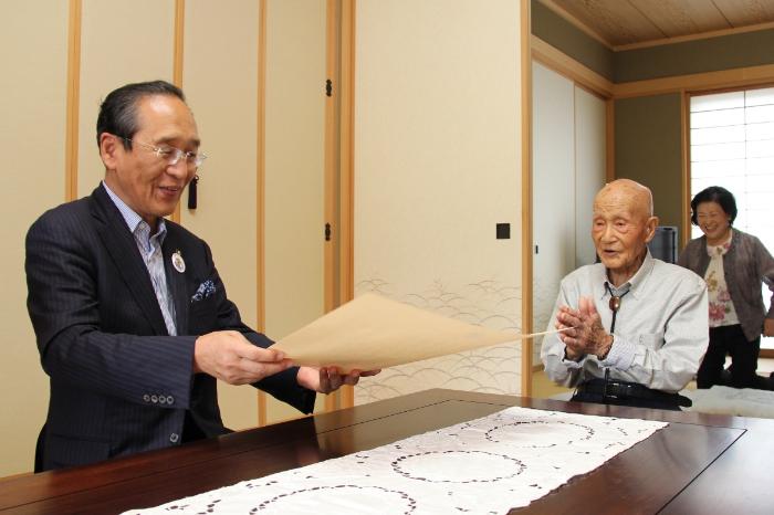 画像　賞状を読み上げる市長と喜ぶおじいちゃん